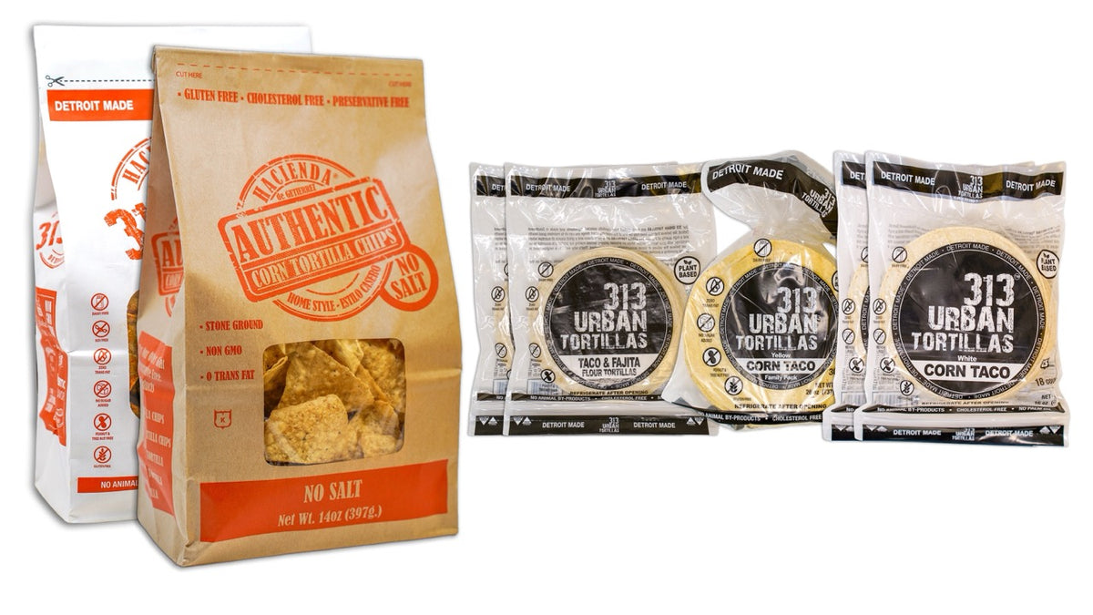 Image: A display featuring one bag of 313 Urban Chili Lime tortilla chips alongside one bag of Hacienda Authentic No Salt tortilla chips on the left. To the right, there are two bags of 313 Urban 6" Flour Tortillas, one bag of 313 Urban Yellow Corn Tortillas, and two bags of 313 Urban White Corn Tortillas, all labeled "Detroit Made."