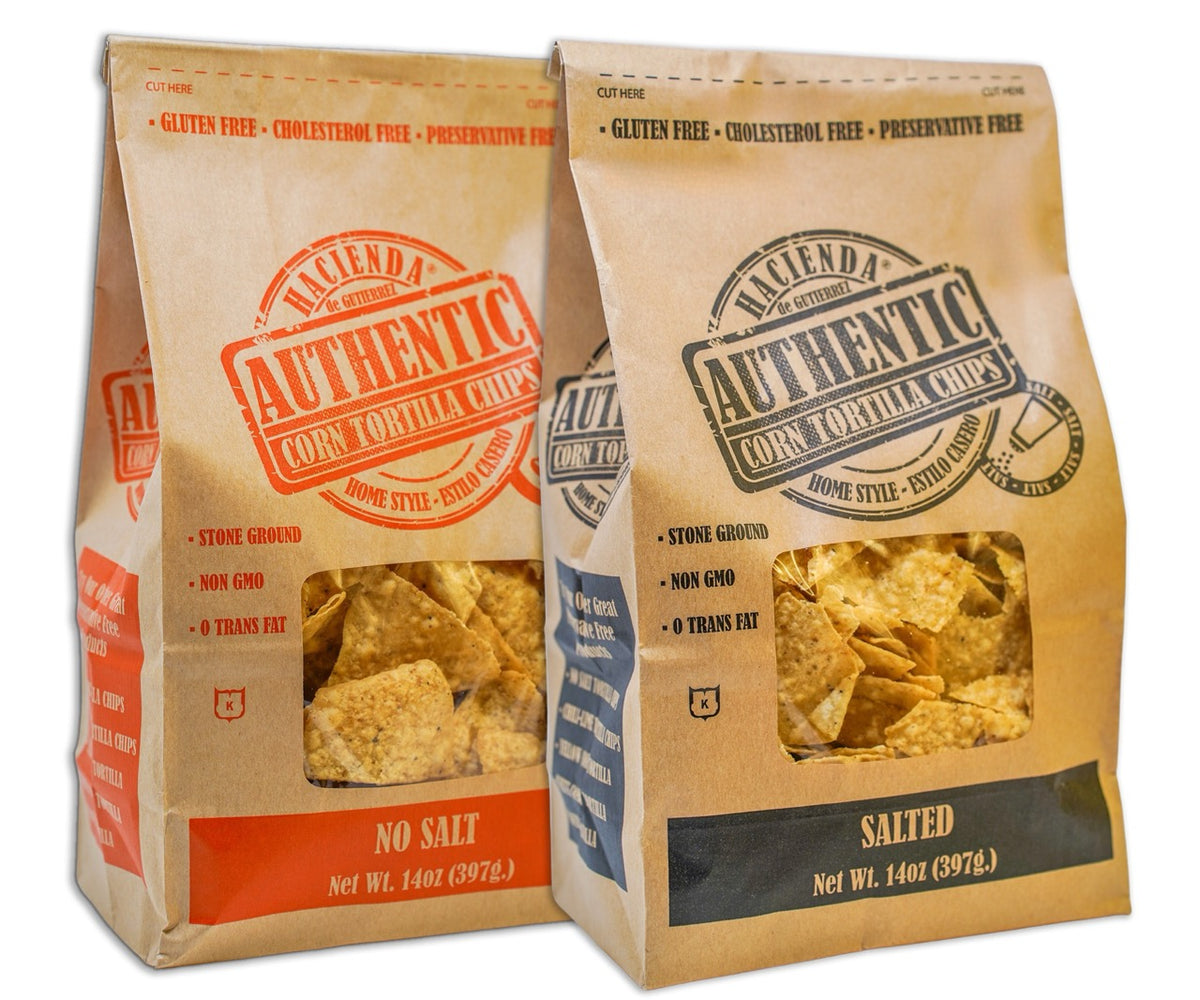 A bag of Hacienda Authentic Corn Tortilla Chips labeled "No Salt" next to a bag labeled "Salted," both featuring a clear window showcasing the chips and the branding that highlights they are "Detroit Made."