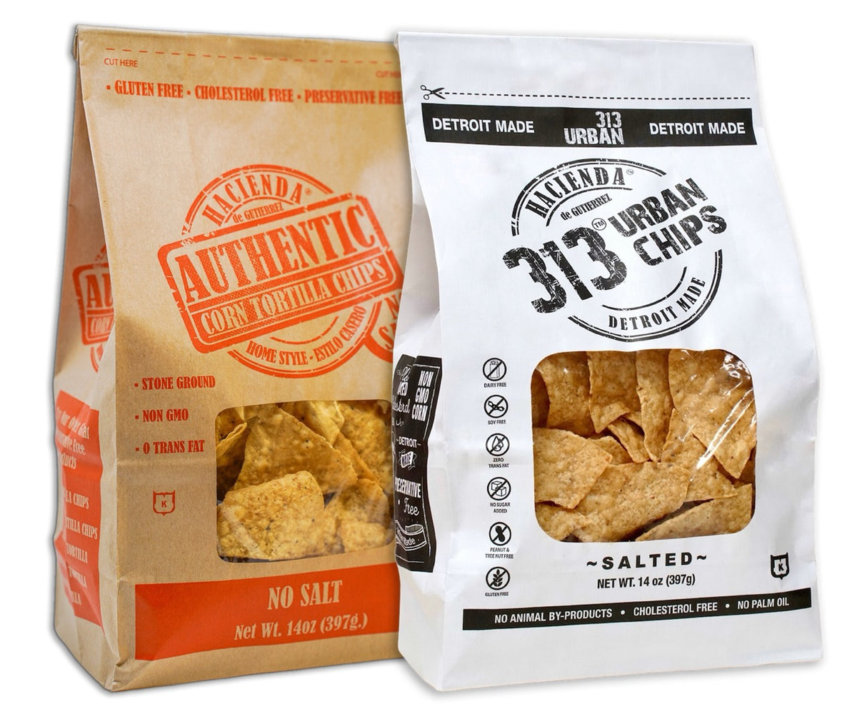 A bag of Hacienda Authentic Corn Tortilla Chips labeled "No Salt" alongside a bag of 313 Urban Salted chips, both with clear windows showing the chips inside and emphasizing they are "Detroit Made."