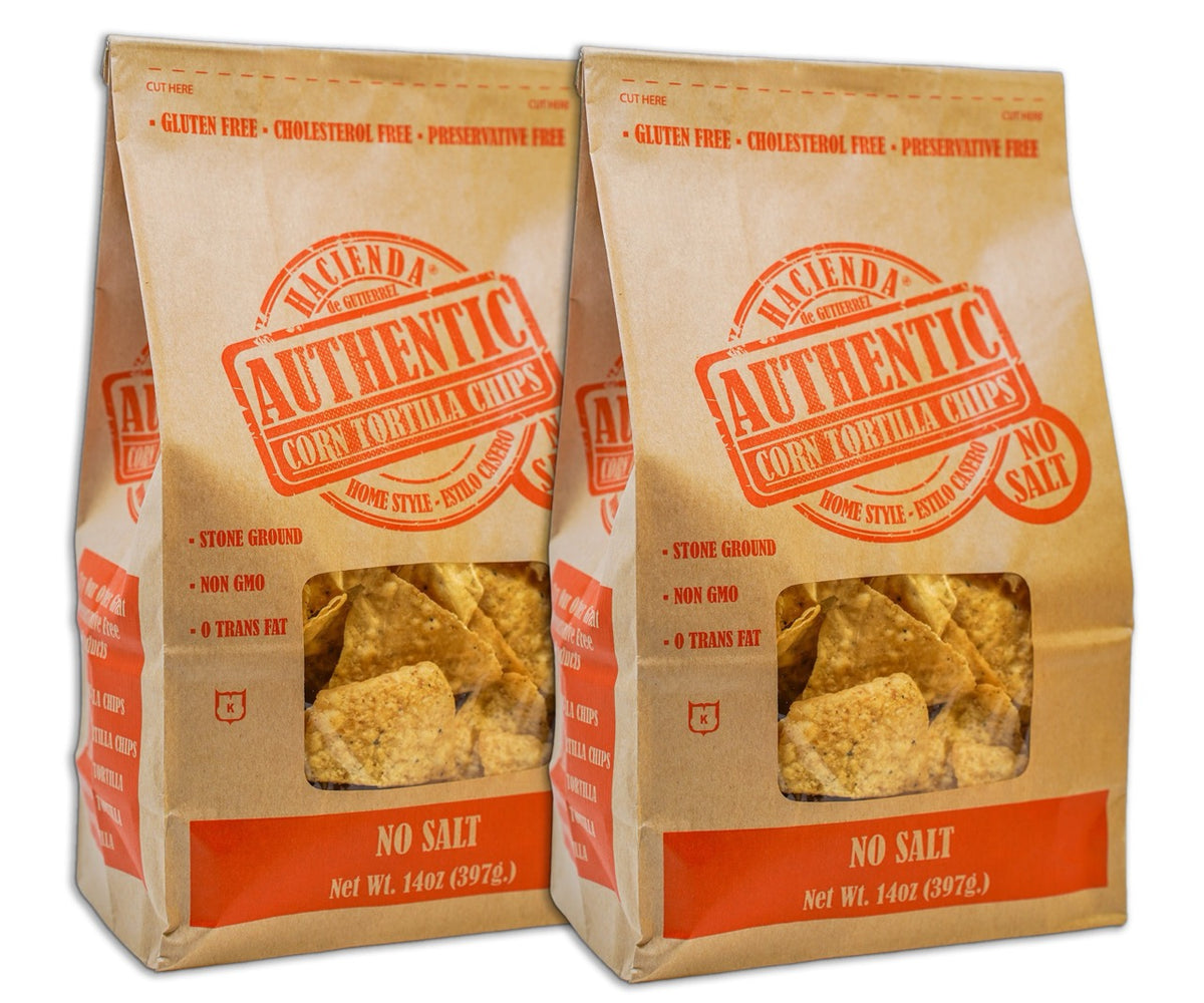 Two bags of Hacienda Authentic Corn Tortilla Chips labeled &quot;No Salt,&quot; featuring clear windows to view the chips inside, highlighting their &quot;Home Style&quot; quality and &quot;Detroit Made&quot; branding.